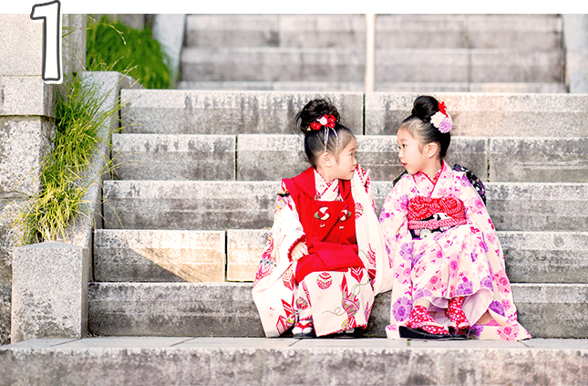 神社の石段に座って七五三写真を撮る、着物を着た3歳と7歳の姉妹